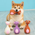 Shiba Inu dog playing with colorful animal-shaped dog toys on wooden floor